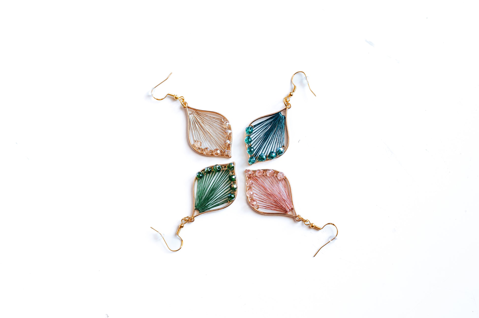 Thread and bead teardrop earrings in rose, champagne, emerald, and peacock blue. Made with hypoallergenic hooks. 