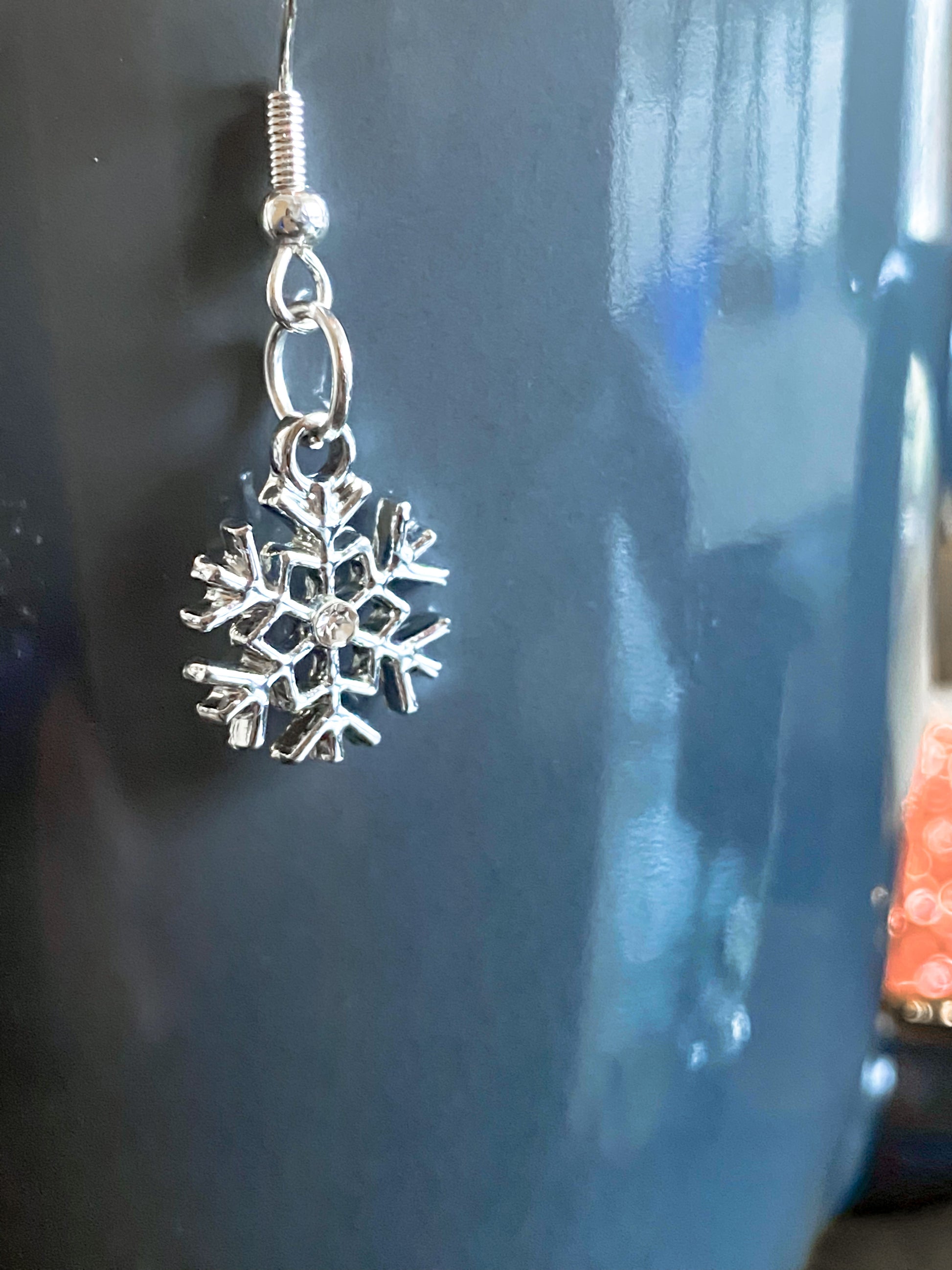 Single earring shown with the six-sided earring and rhinestone middle. set against dark background.